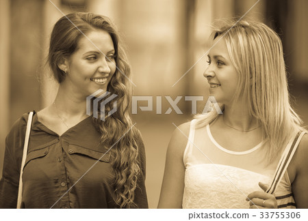 Two cheerful girls walking in city . 33755306