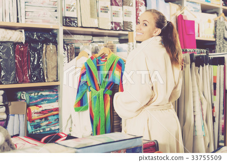 Smiling girl shopper examining new bathrobe 33755509