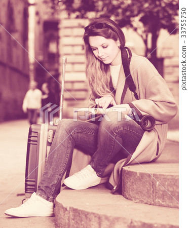 traveling girl searching for the direction using a booklet in the town 33755750