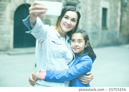 Smiling mother and daughter taking photo Smiling mother and daughter taking photo 33755856