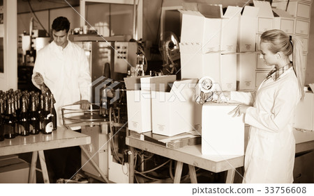 female packing bottles on winery . 33756608