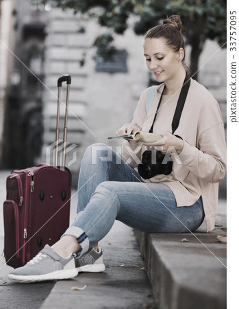 Female tourist is sitting down on curb 33757095
