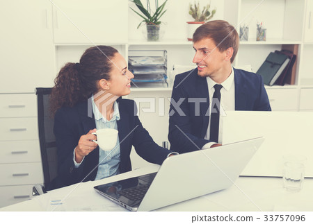 young man and cheerful woman coworkers talking in firm office 33757096