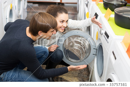 couple choosing washing machine in hypermarket and smiling 33757381