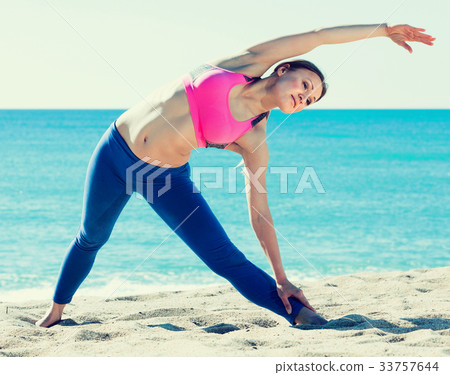 Positive female stretching muscles on the sand 33757644