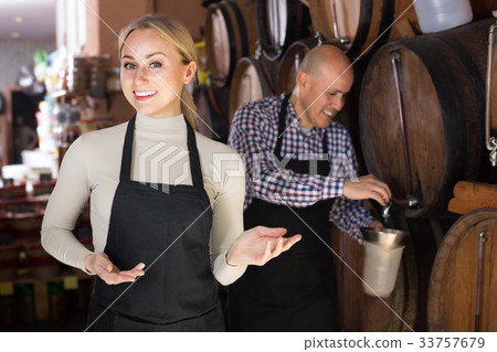 Cheerful mature man and young woman posing with wine from wood Cheerful mature man and young woman posing with wine from wood 33757679