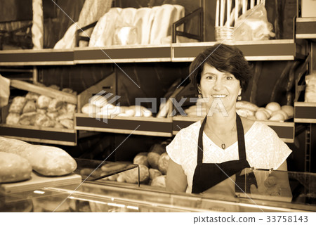 attentive female baker with fresh bread in bakery 33758143