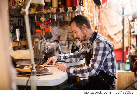 Male worker stitching new belt 33758292