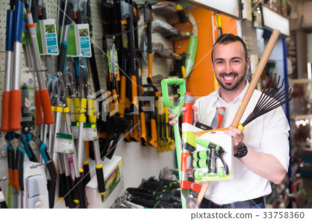 Man selecting gardening equipment in store. 33758360