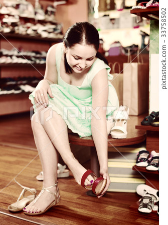 Girl is trying on heeled sandals in shoes shop Girl is trying on heeled sandals in shoes shop 33758502
