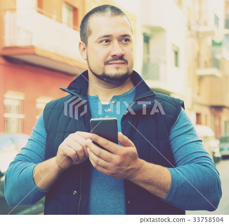 attractive man in city with phone in his hands attractive man in city with phone in his hands 33758504