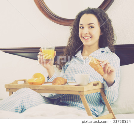 Adult girl with juice and croissant in bed Adult girl with juice and croissant in bed 33758534