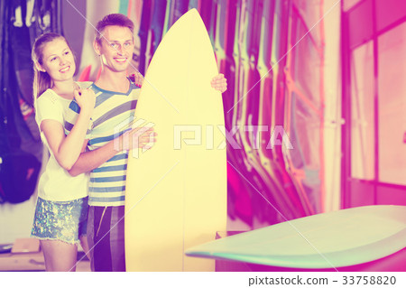 Couple is satisfied of colorful boards in store on the beach. 33758820