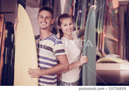 Young man and woman standing with new surfboards Young man and woman standing with new surfboards 33758839