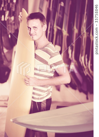 male is posing with surfboard in store on the beach. male is posing with surfboard in store on the beach. 33758846
