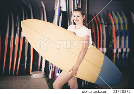 Sport girl surfer holding new surfboard in nautical store Sport girl surfer holding new surfboard in nautical store 33758872