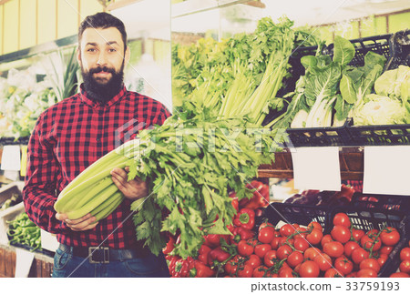 Shop assistant demonstrating celery Shop assistant demonstrating celery 33759193