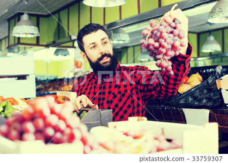 Shop assistant demonstrating grapes 33759307