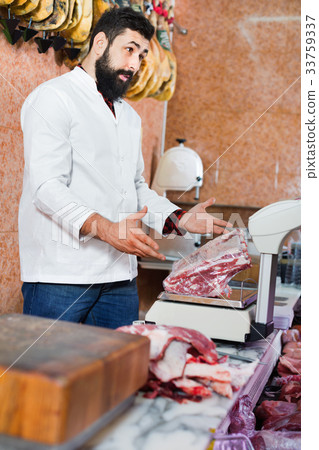 Man seller using scales for meat to sell in butcher’s shop 33759337