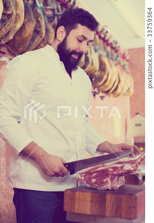 Male shop assistant carving meat 33759364