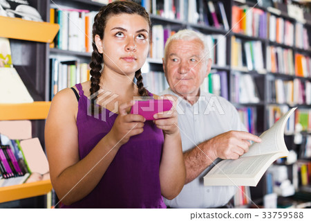 Old man is choosing book while granddaughter chatting Old man is choosing book while granddaughter chatting 33759588
