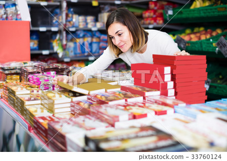 friendly girl customer looking for tasty sweets in supermarket 33760124