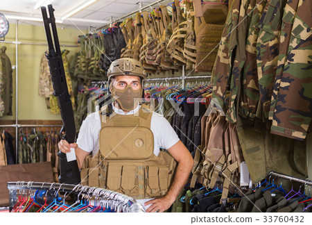 Young guy in military equipment with gun in airsoft shop 33760432