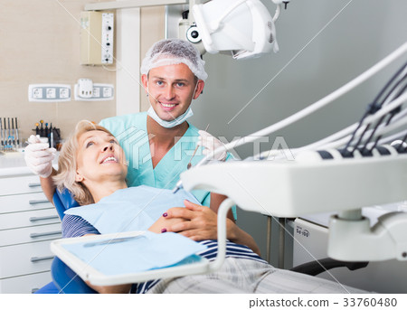 Male dentist treating female patient 33760480