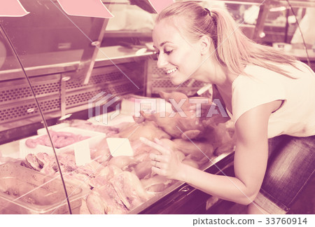 Cheerful woman customer looking at chicken parts Cheerful woman customer looking at chicken parts 33760914