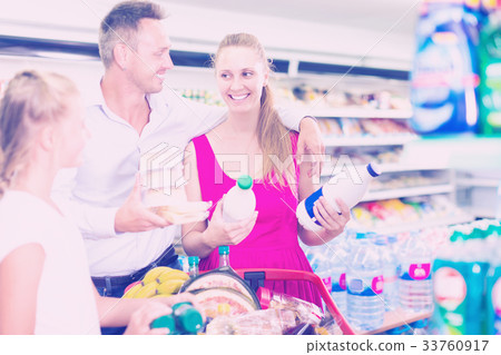 Young family with girl buying milk in food shop Young family with girl buying milk in food shop 33760917