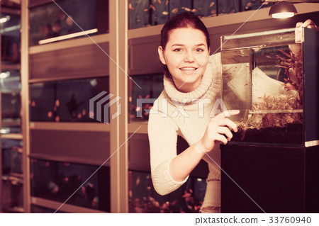 Teenage girl shows an aquarium with fish fry Teenage girl shows an aquarium with fish fry 33760940