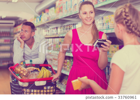 woman and daughter with purchases in shopping cart . man on backgound woman and daughter with purchases in shopping cart . man on backgound 33760961