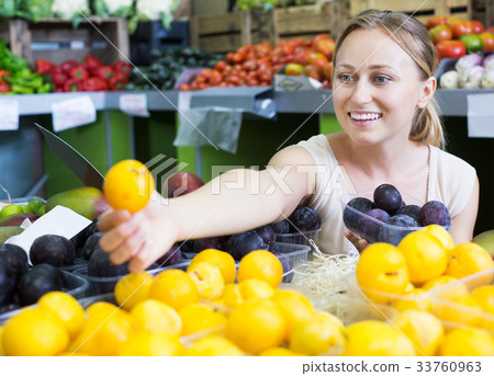 Woman looking plums in fruit store 33760963