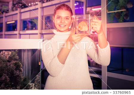 Girl keeps big tropical fish in plastic container Girl keeps big tropical fish in plastic container 33760965