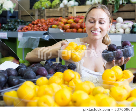 young woman buying plums at market. 33760967