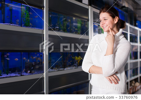 Teenage girl is thinking and solving what breed of aquarium colorful fish to buy Teenage girl is thinking and solving what breed of aquarium colorful fish to buy 33760976