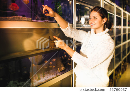 Girl in aquarium shop points to colored fish 33760987