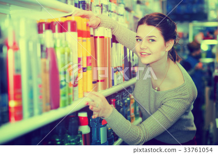 Smiling woman customer deciding on hair care products in shop 33761054