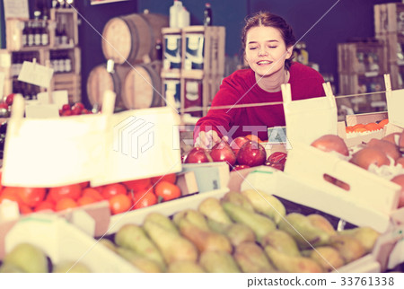 Portrait of young brunette girl buying apple in supermarket 33761338