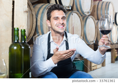 male seller holding glass on wine in cellar . male seller holding glass on wine in cellar . 33761361