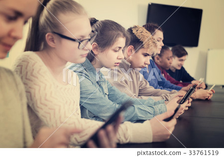 Classmates using their smartphones heavily during classes Classmates using their smartphones heavily during classes 33761519