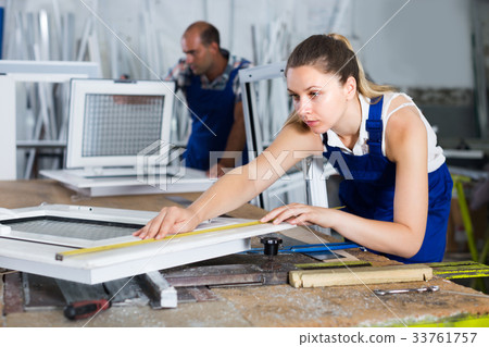 Woman is checking dimensions of finished plastic window using measuring tape Woman is checking dimensions of finished plastic window using measuring tape 33761757