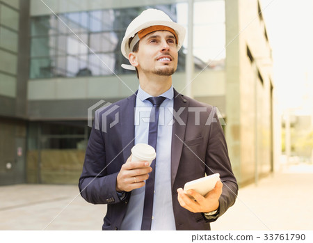 Cheerful architect in helmet working at touchpad Cheerful architect in helmet working at touchpad 33761790