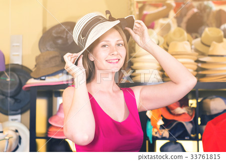 adult smiling woman try on boater hat in shopping mall 33761815