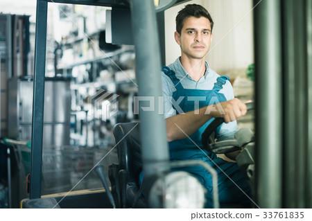 concentrated man in unifom is using сargo moving machine in the building store concentrated man in unifom is using сargo moving machine in the building store 33761835