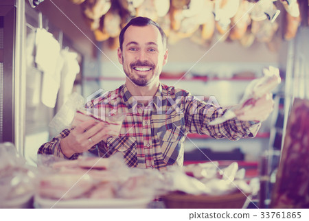 Smiling male assistant showing sorts of meat Smiling male assistant showing sorts of meat 33761865