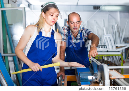 Craftsman is explaining work on circular saw to young worker woman 33761866