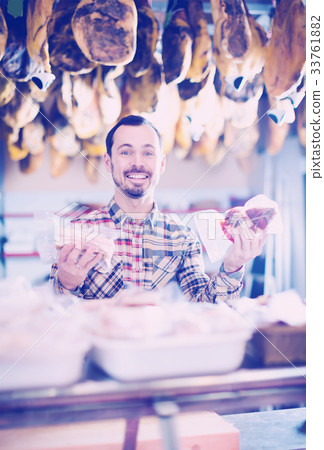 happy male shop assistant demonstrating sorts of meat in shop happy male shop assistant demonstrating sorts of meat in shop 33761882