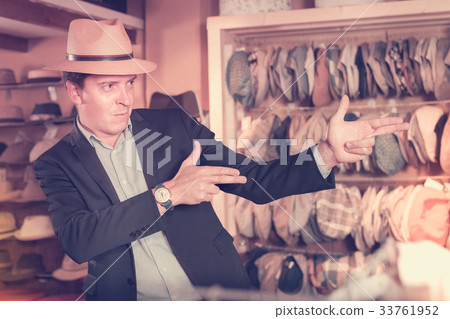 portret of smiling young guy try on panama at headwear store 33761952