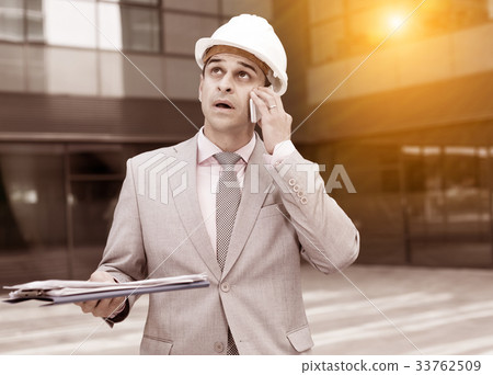 Businessman with papers emotionally talking on phone 33762509
